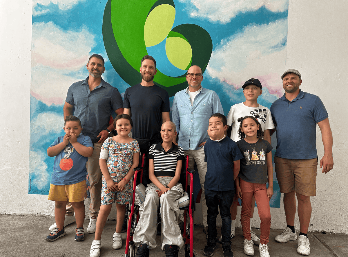 The Senga Energy team with children from Mi Gran Esperanza in front of the heart logo mural