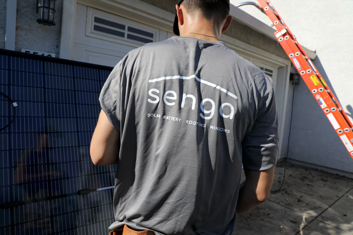Senga Energy installer in a branded shirt working next to solar panels during a rooftop installation at a Northern California home